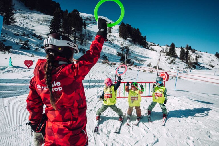 Skilehrerin macht mit den Kindern Übungen während des Skikurses