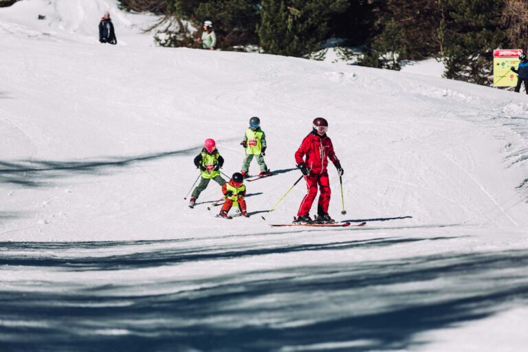 Kinder beim Skifahren mit Skilehrer während eines Skikurs in Obertauern