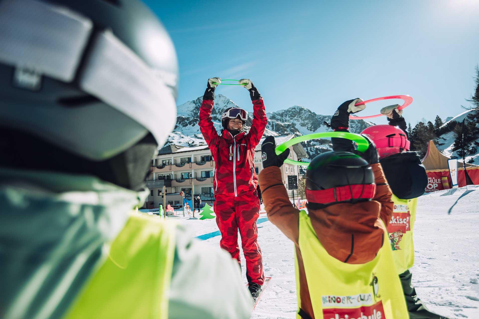 Skilehrer hat Spaß mit den Kindern bei den Übungen während des Skikurs